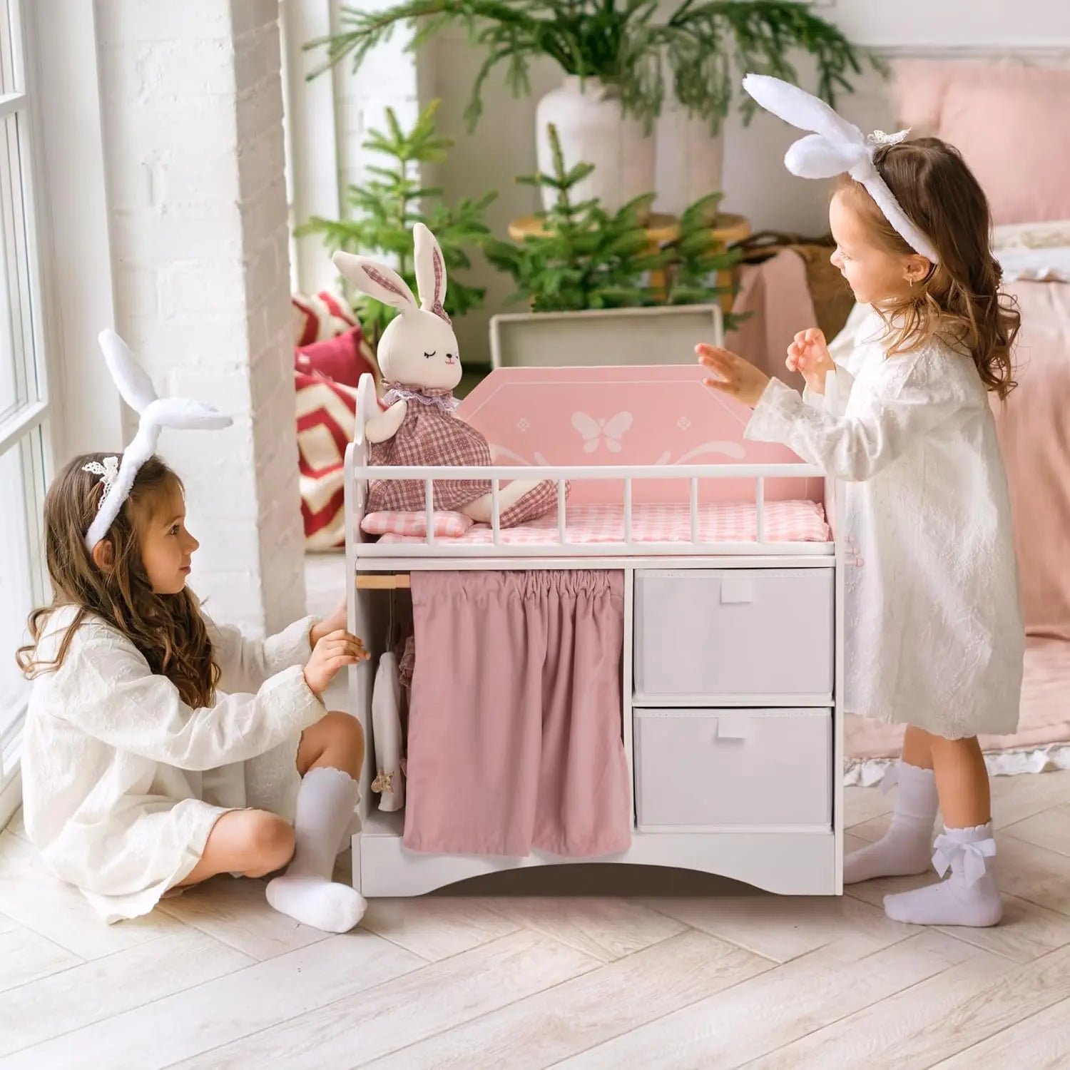 Two children playing with a baby crib in a bright, decorated room.