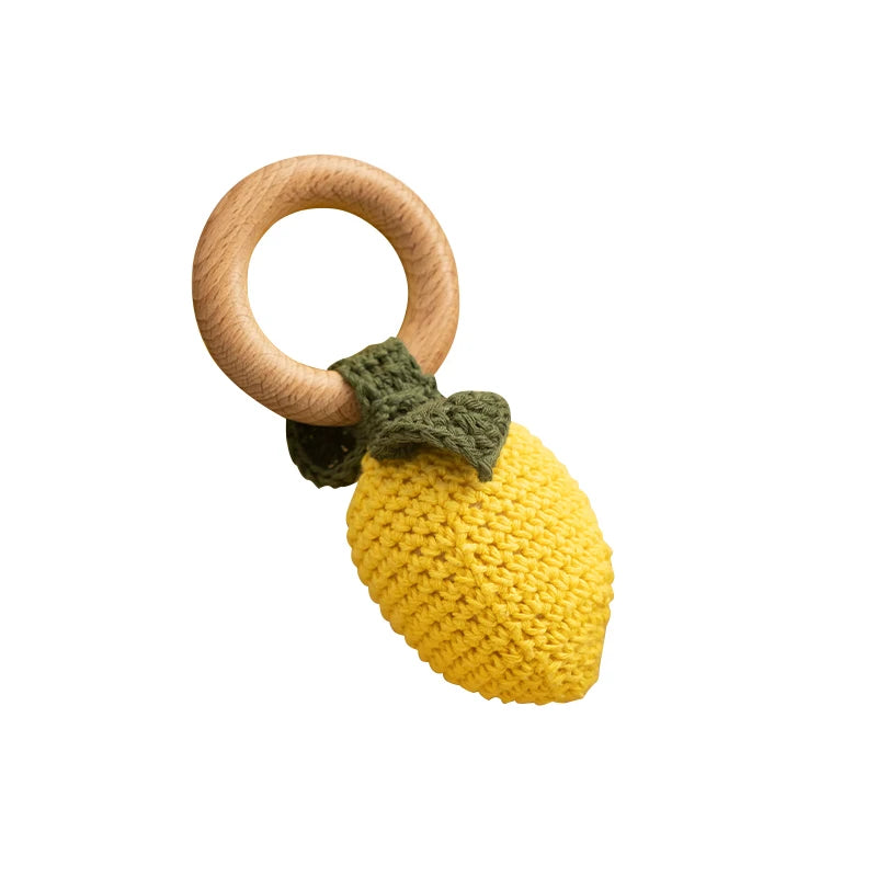 Yellow lemon-shaped teething ring with a wooden ring on a white background