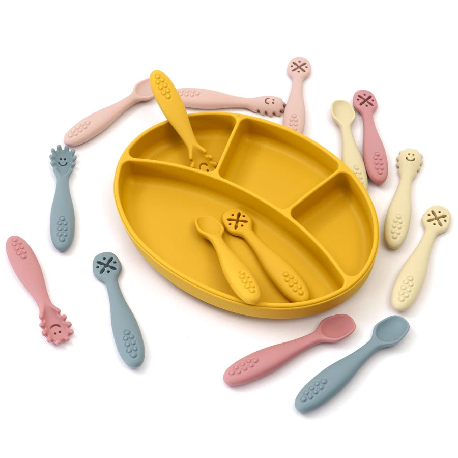 Silicone learning spoons around a yellow divided plate