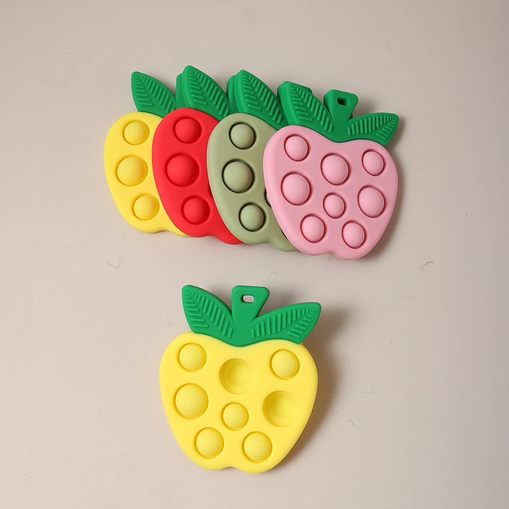 Set of colorful pop-it toys shaped like fruits on a beige background