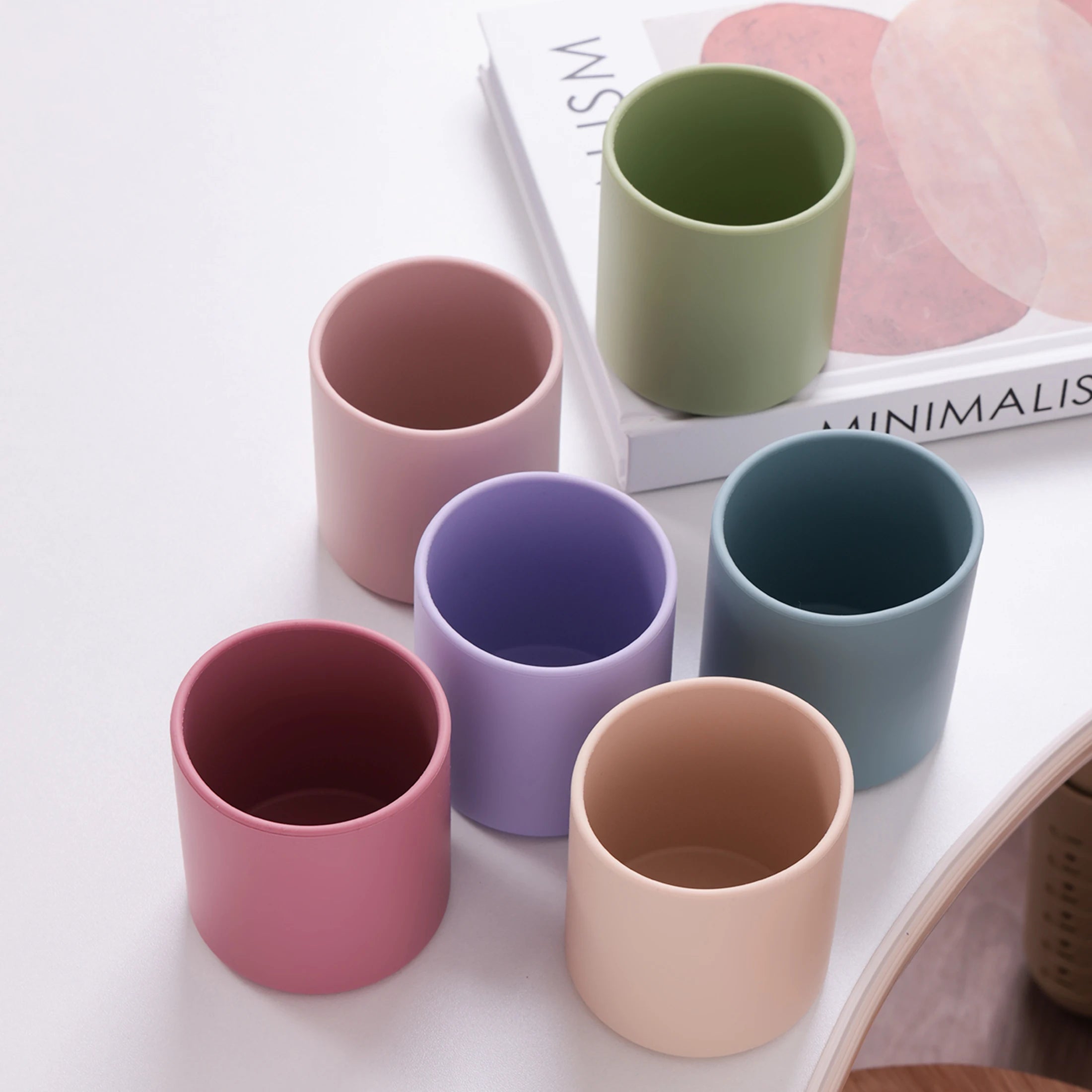 Silicone open training cups in soft colors on a table