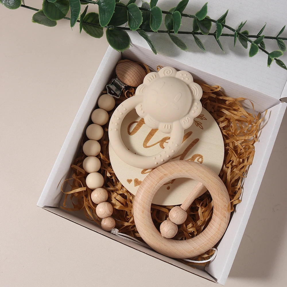 Set of baby teething rings and beads in a decorative box with a plant branch on a light background