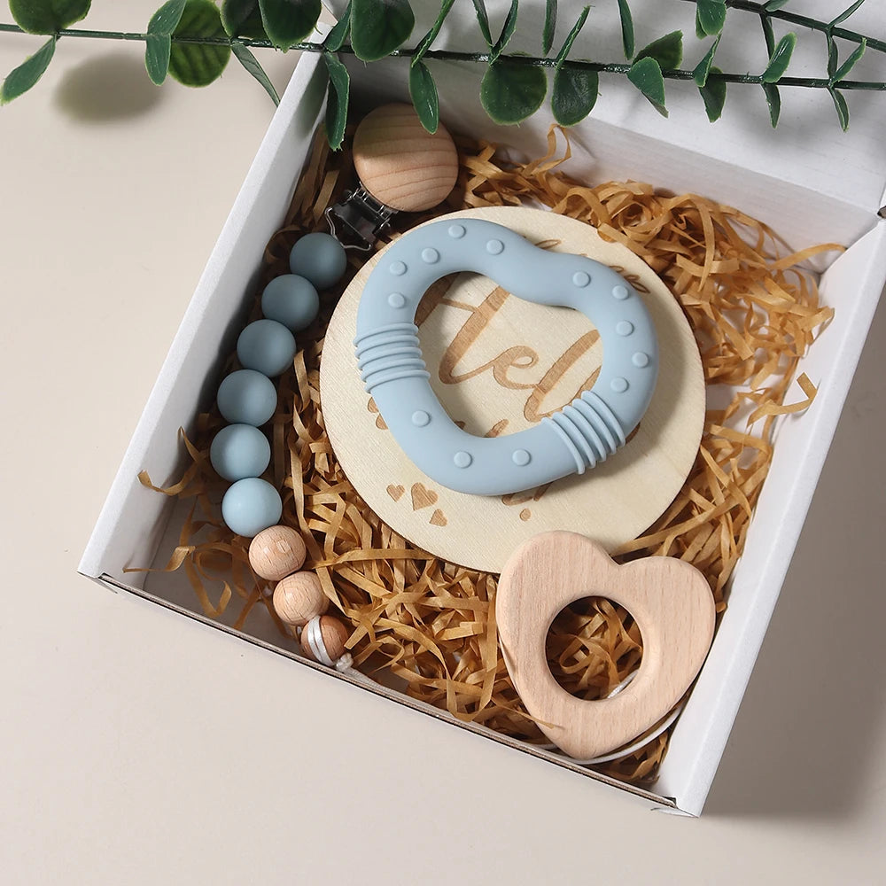 Set of baby teething toys in a decorative box with plants in the background
