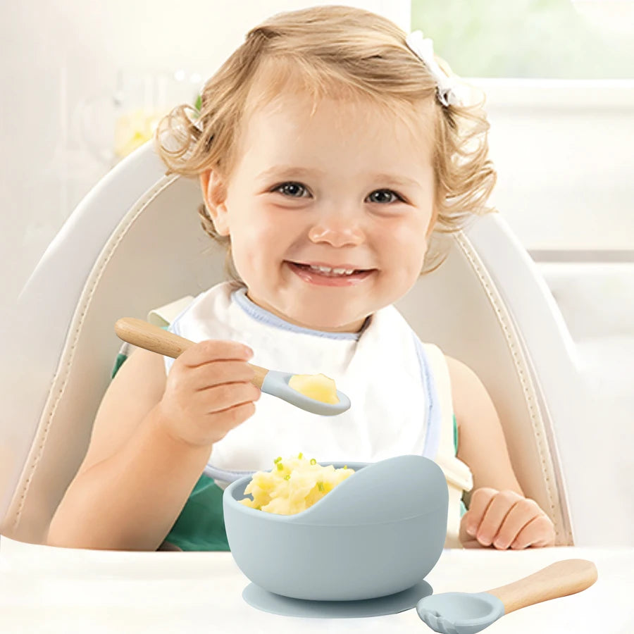 Light grey suction bowl at mealtime with a wooden spoon