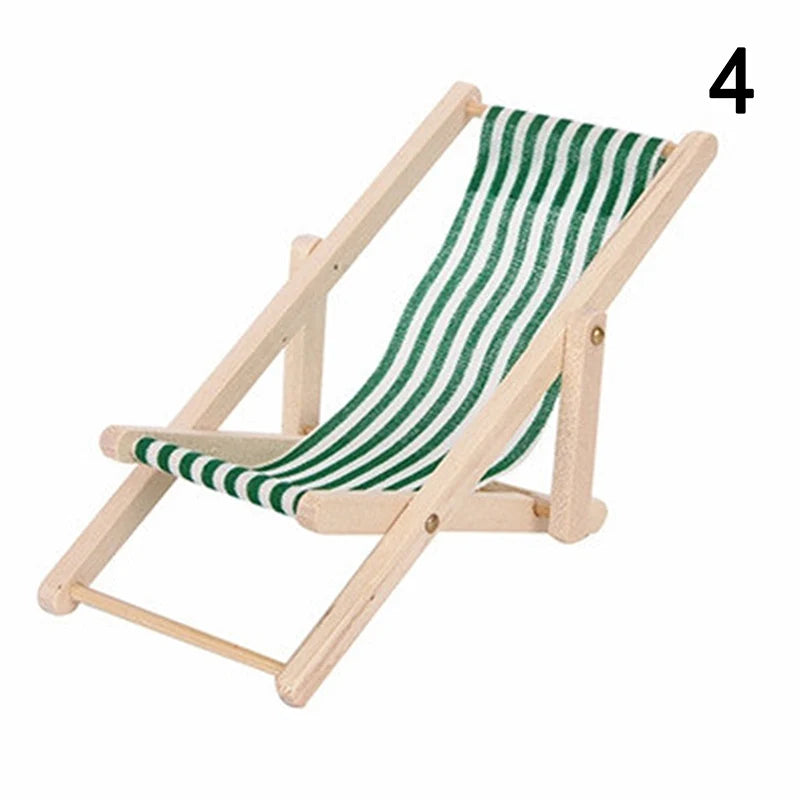 Miniature wooden deck chair with green and white striped fabric on a white background