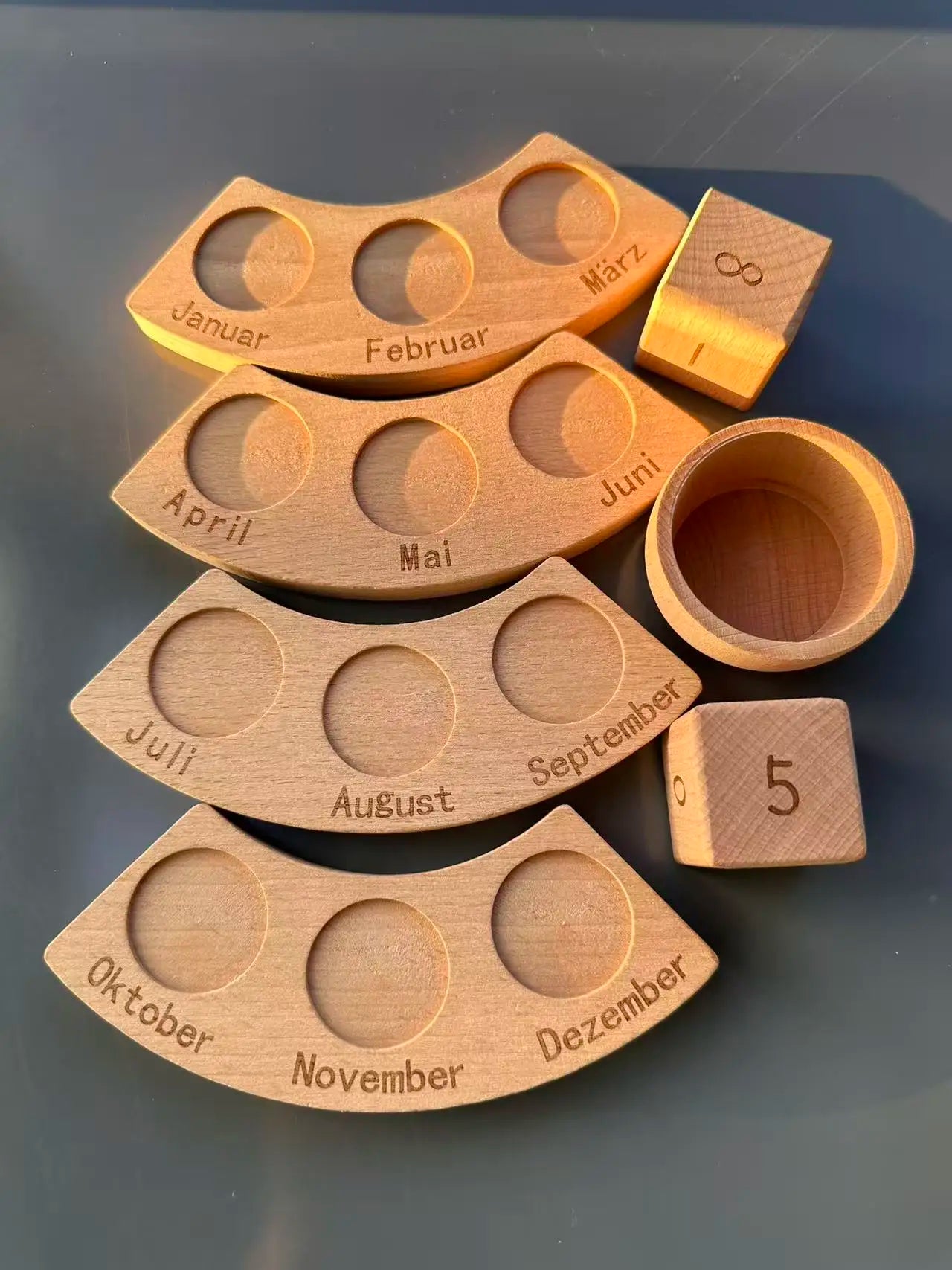 Wooden calendar with months and a dice on a dark surface