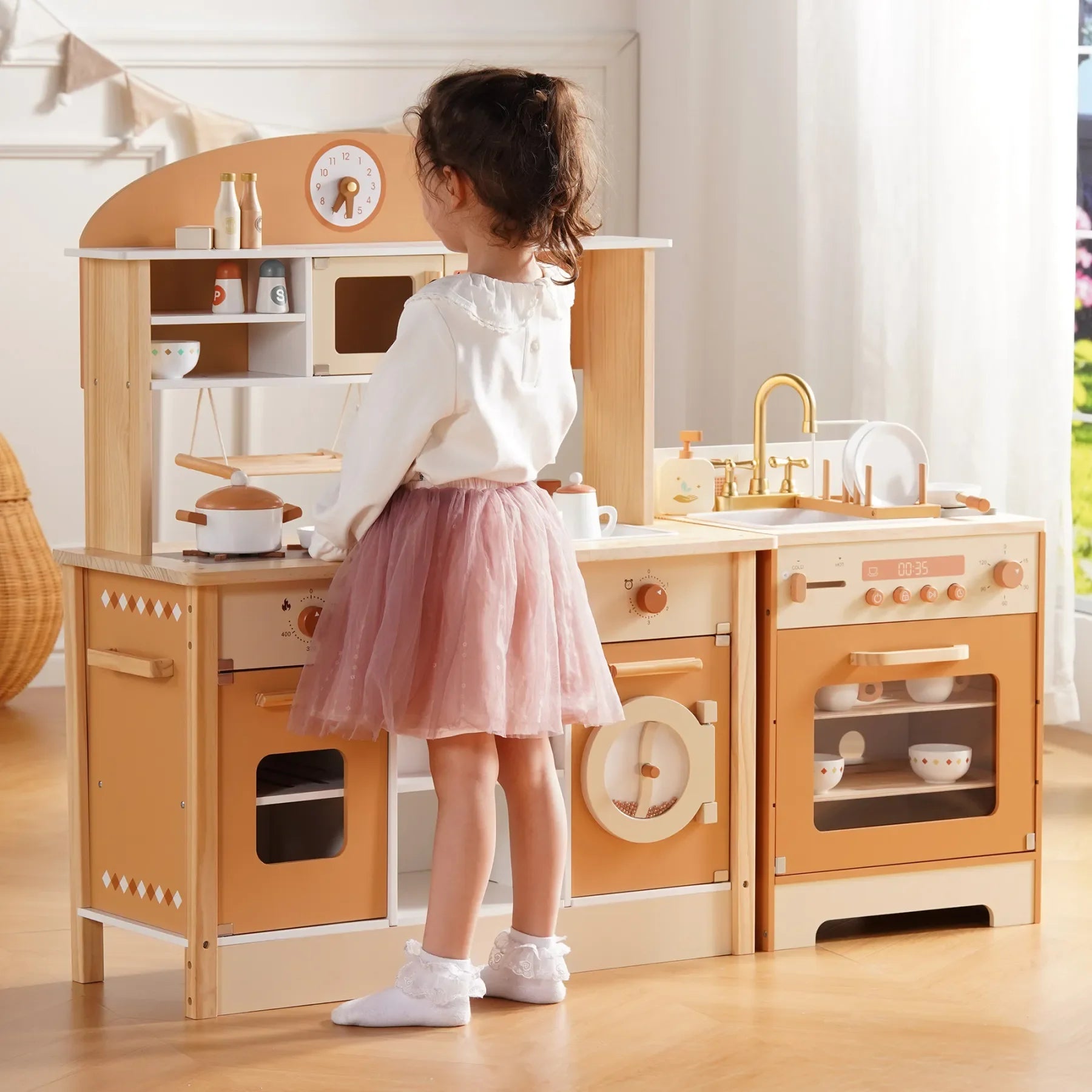 Child playing with a wooden play kitchen set in a bright room.