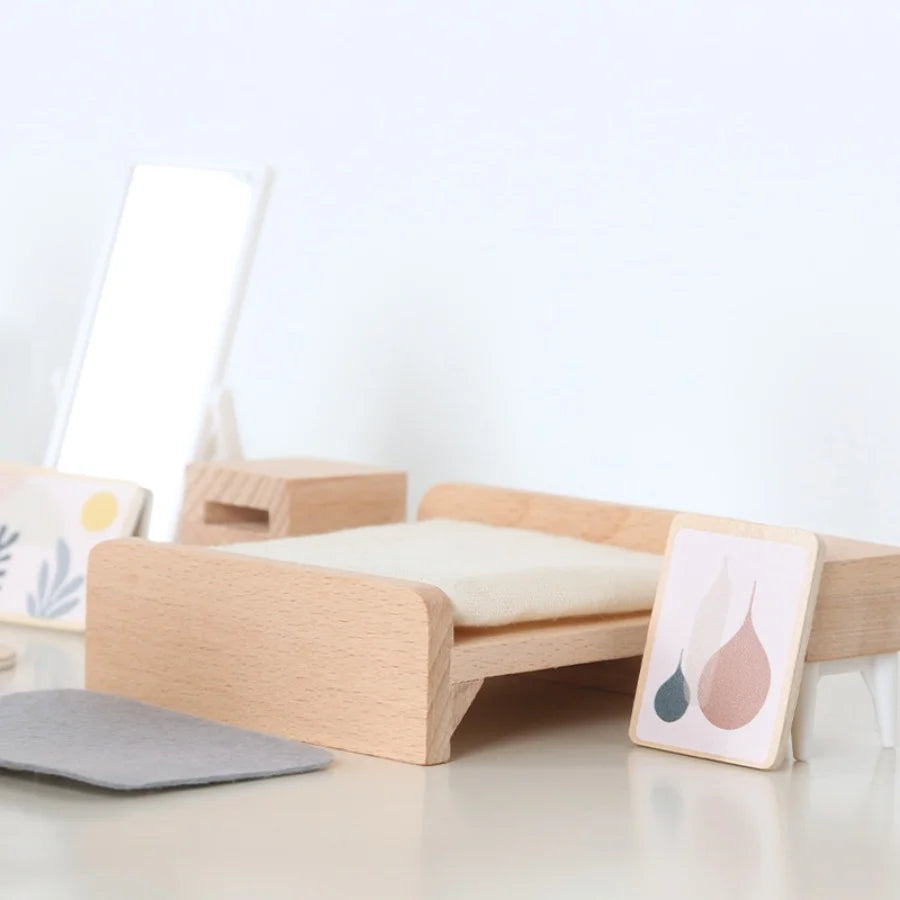 Wooden children's bed with white mattress on a light gray surface, minimal background