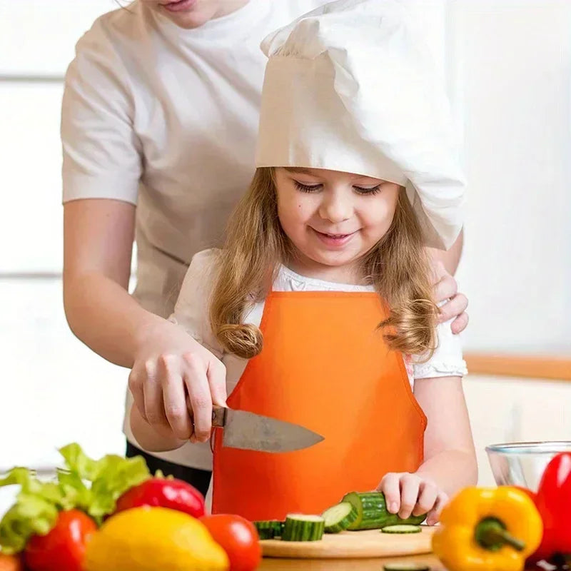 Child in an orange apron learning to cook with a knife, supervised by an adult.