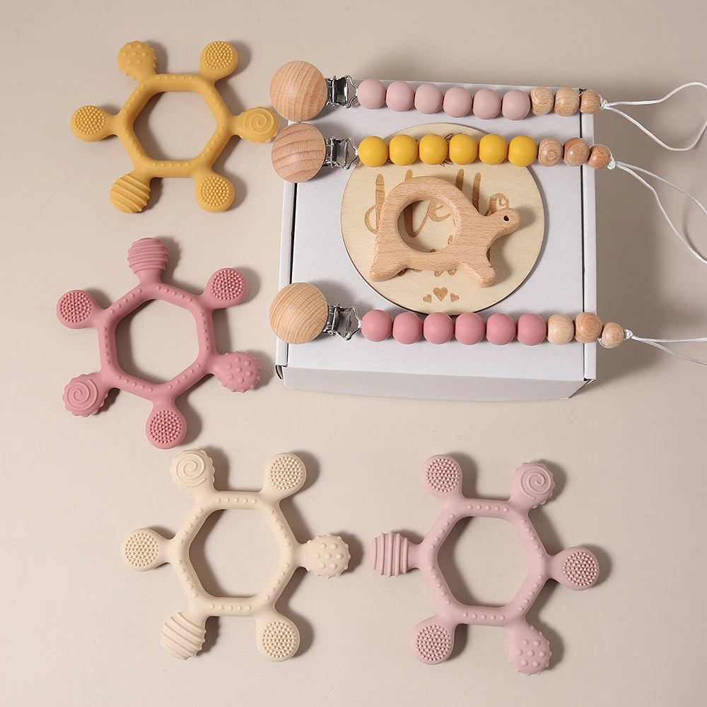 Collection of baby teething toys including silicone and wooden ones on a beige background.