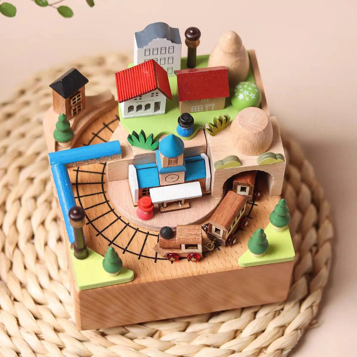 Wooden toy town with houses, roads, and a train on a woven surface