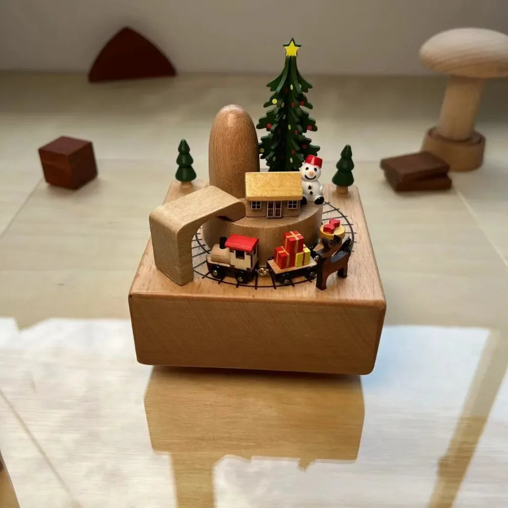 Wooden music box with miniature Christmas scene on a reflective surface