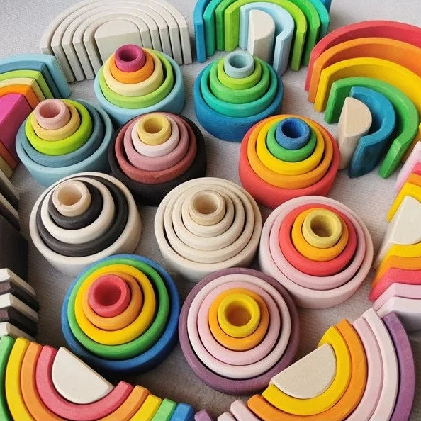 Colorful wooden toys including rainbow shapes and circular blocks on a light surface.