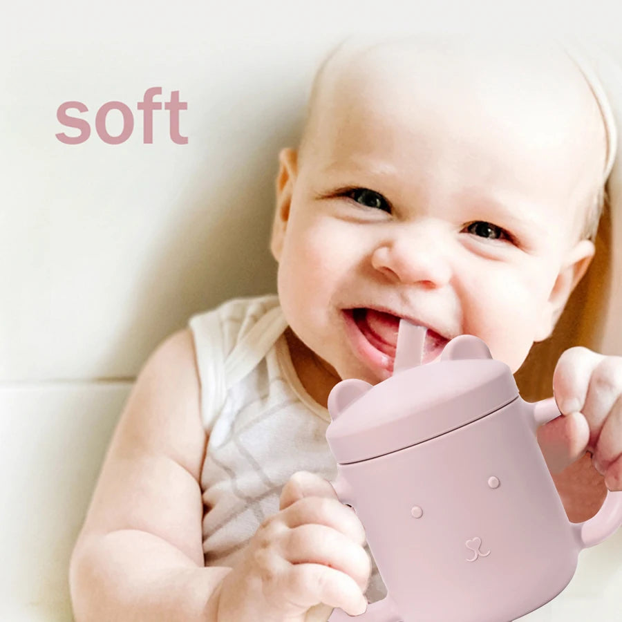 Baby drinking from a pink silicone bear straw cup