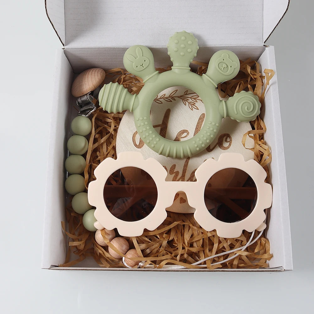 Baby teether and sunglasses set in a gift box with decorative elements.