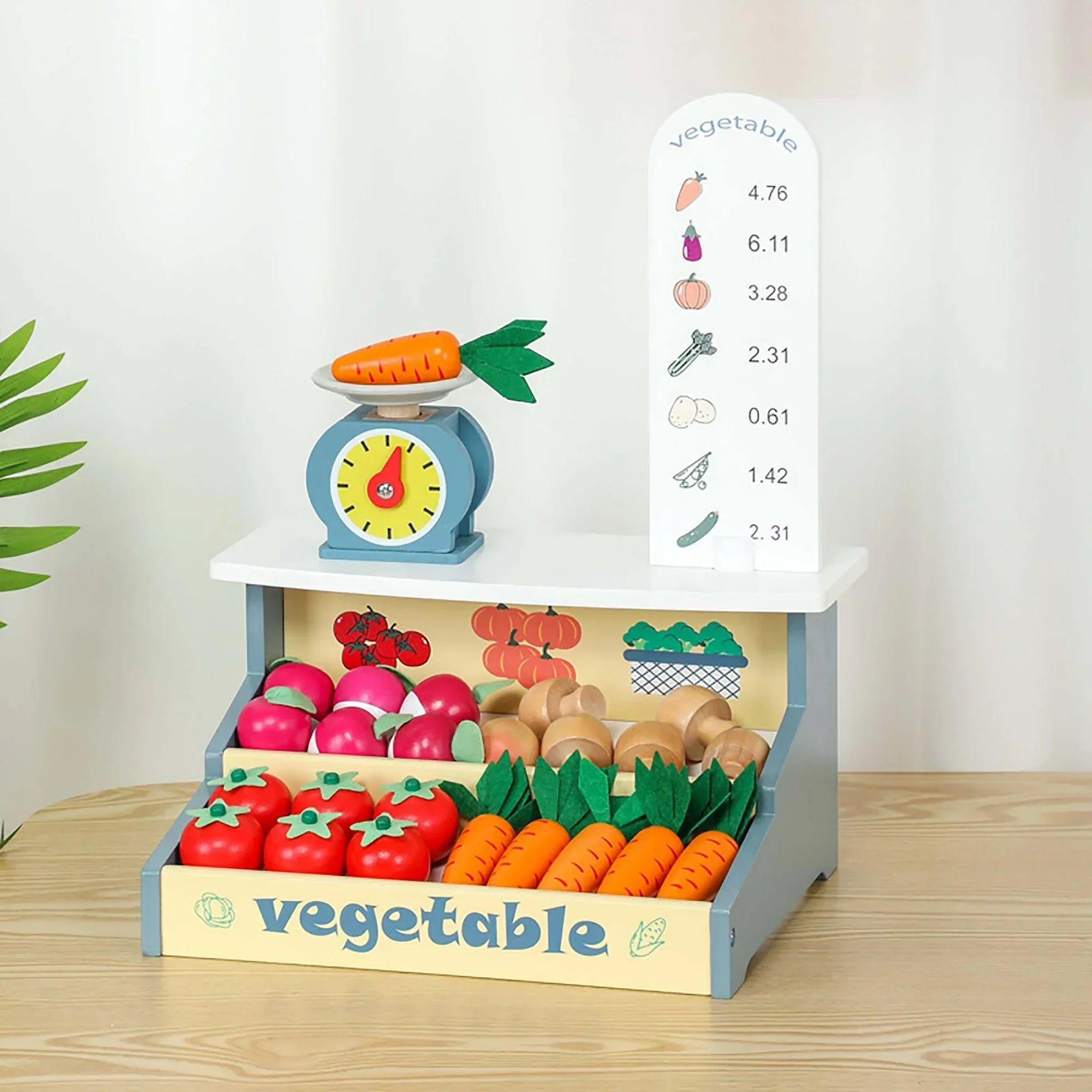 Toy vegetable stand with fruits, vegetables, and a scale on a wooden surface.