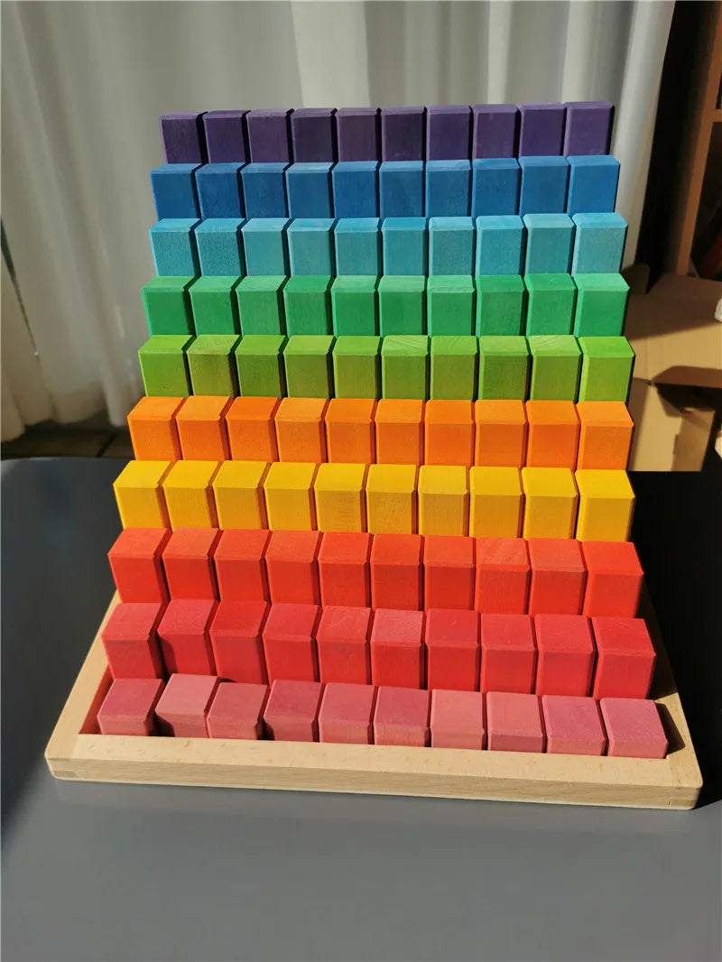 Stack of colorful square blocks on a wooden base against a neutral background