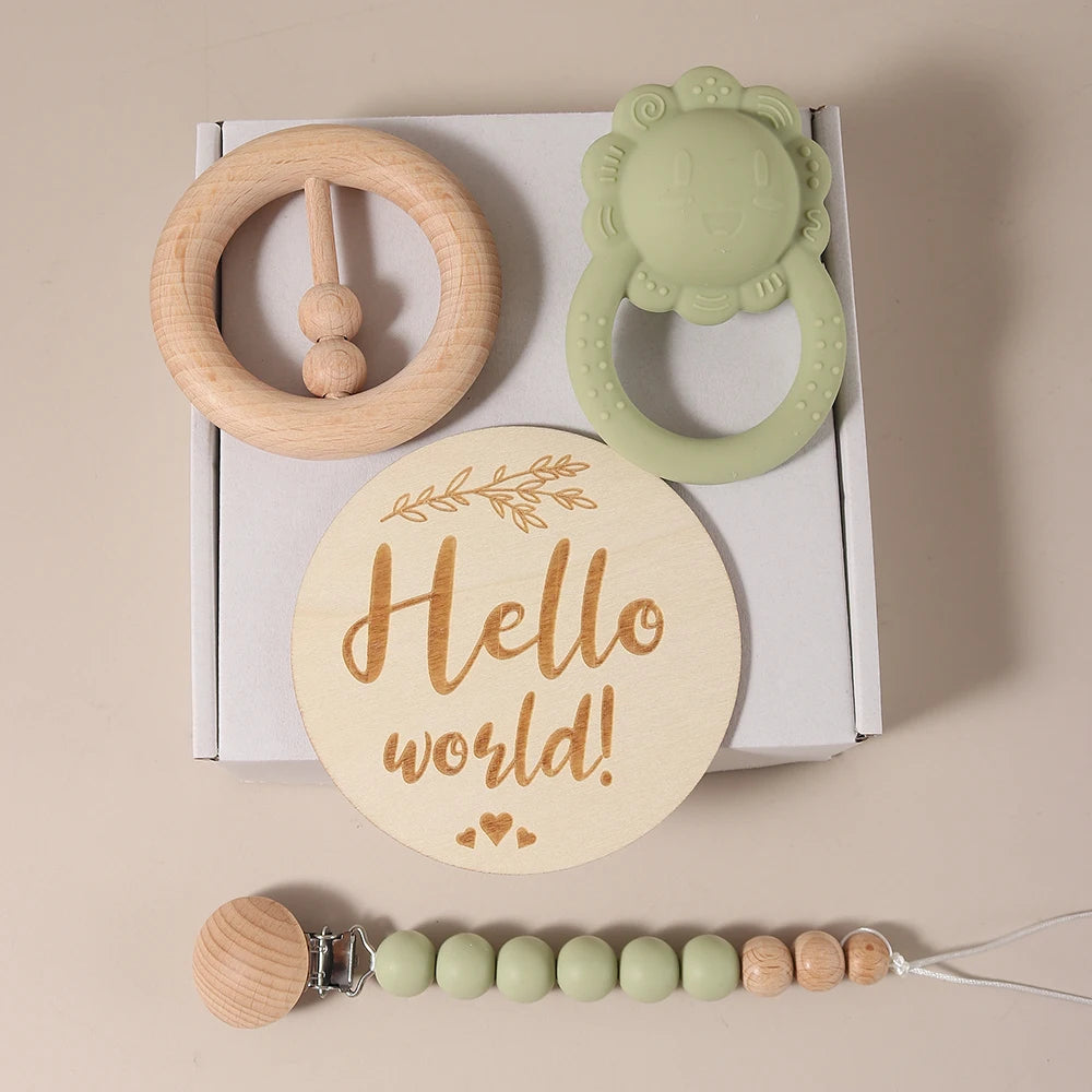 Baby teething ring set with wooden and silicone designs, including a 'Hello world!' disc, on a beige background.
