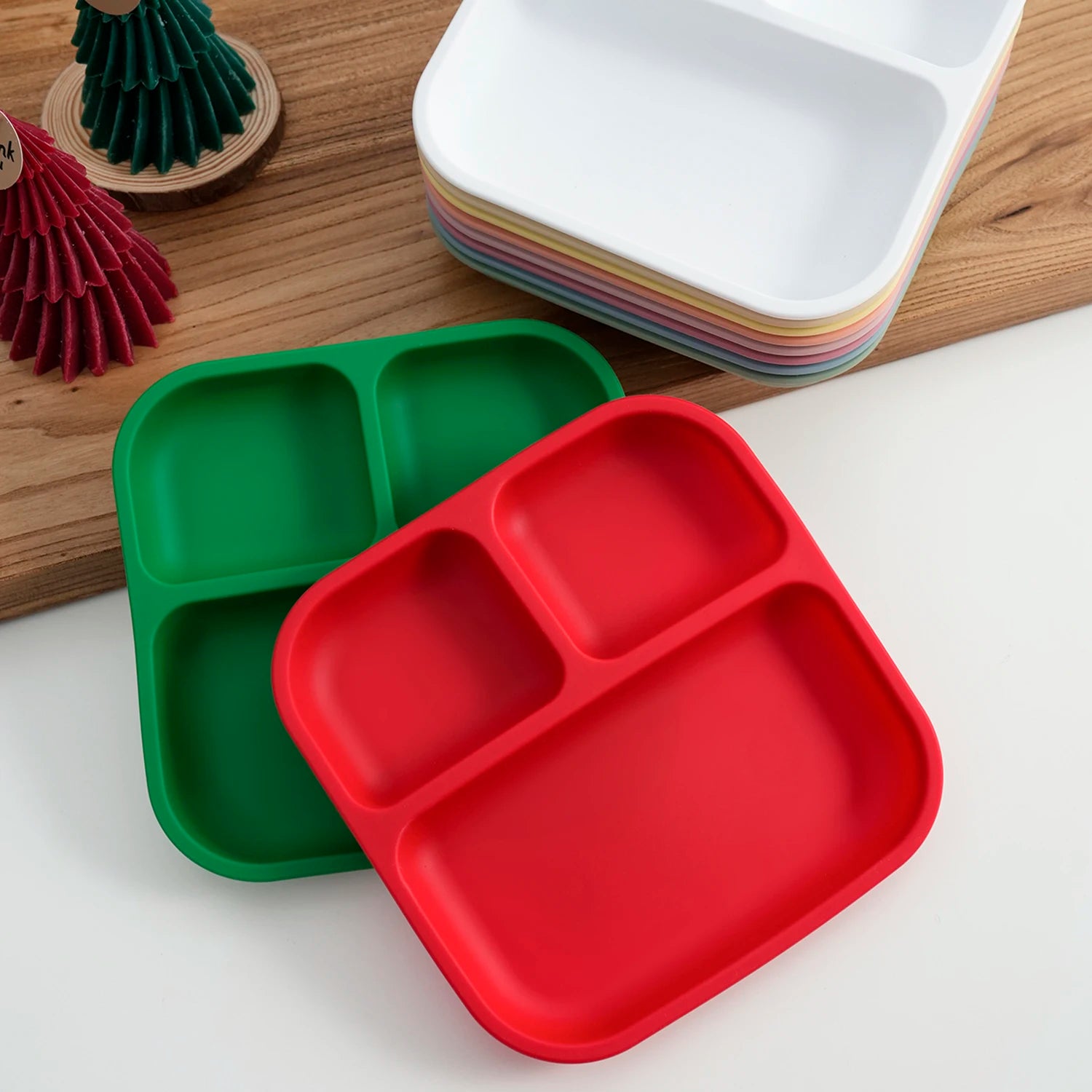Red and green square silicone divided suction plates on a table with Christmas decor