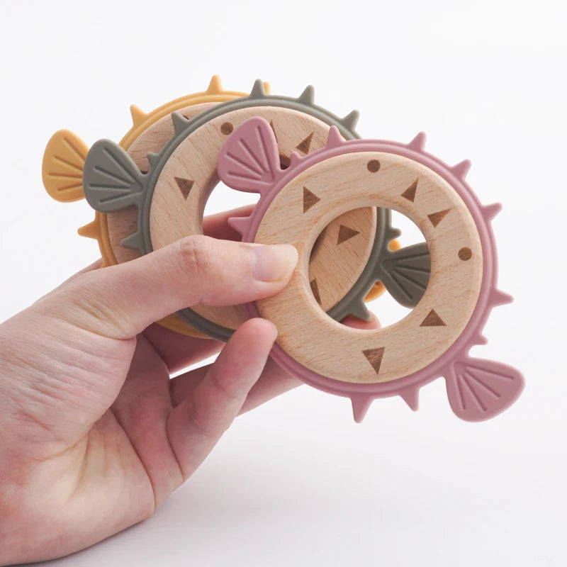Hand holding three pufferfish wooden ring teethers
