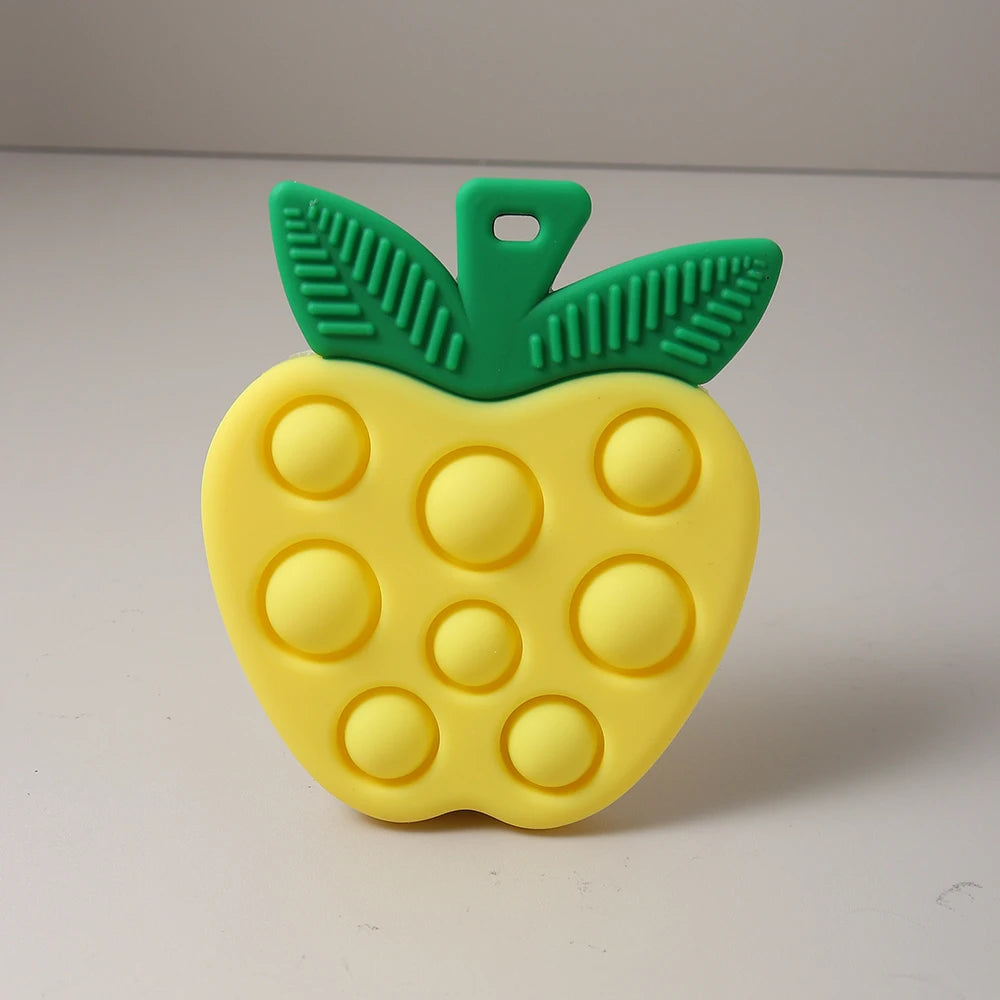 Yellow pop-it toy shaped like an apple with green stem on a white background