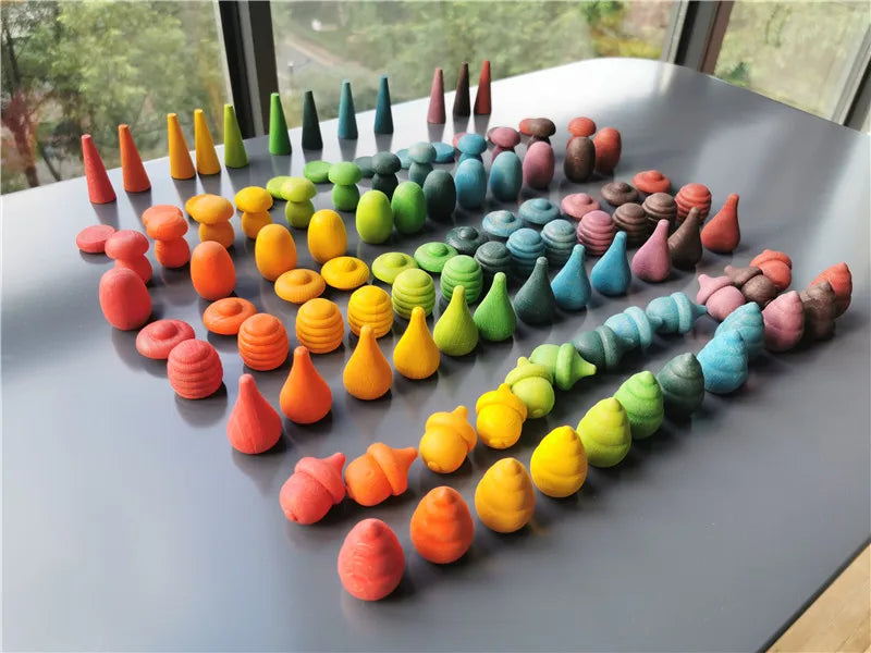 Colorful cwooden loose parts toys arranged on a flat surface with a window in the background