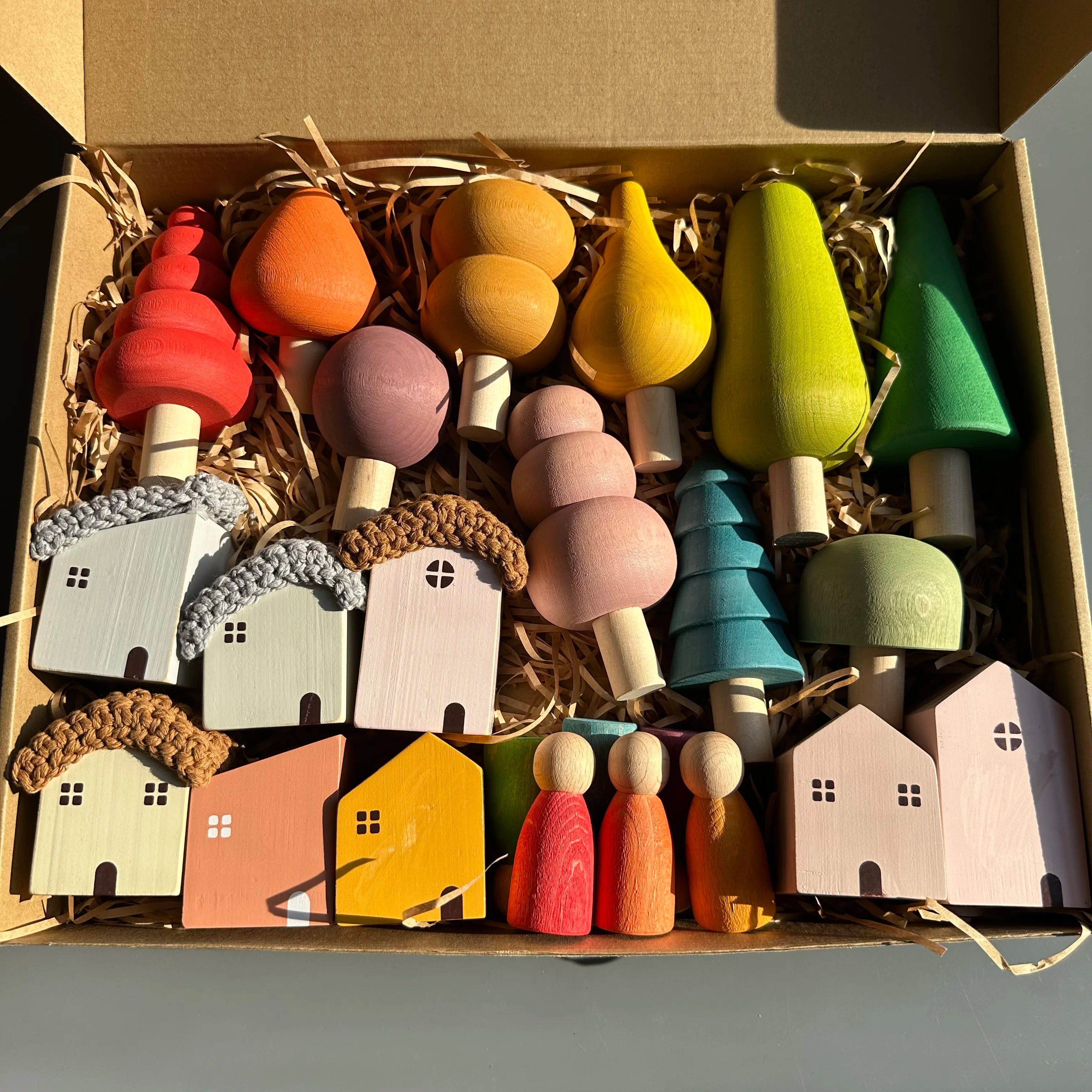 Colorful wooden toy houses and figures in a box