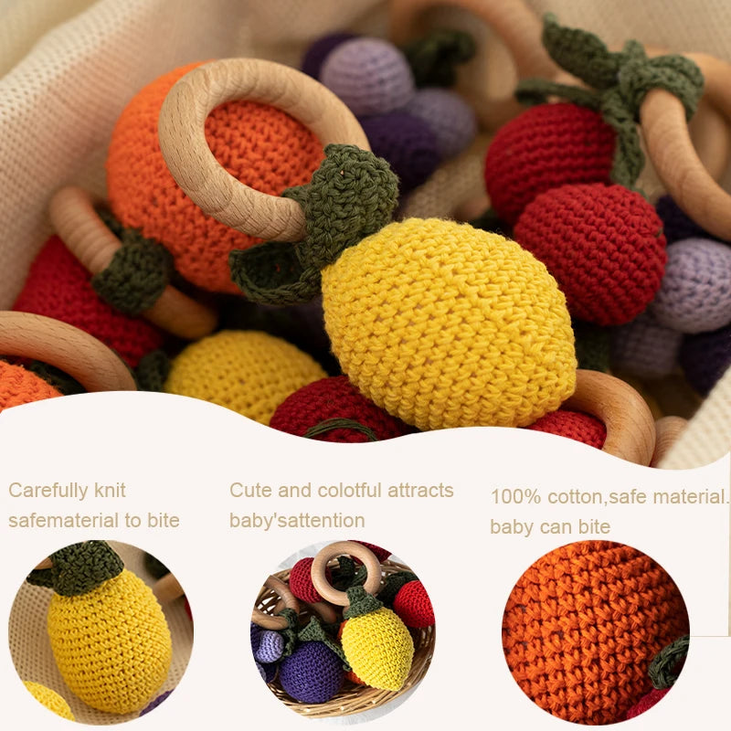 Colorful crochet fruit toys with wooden rings on a white background