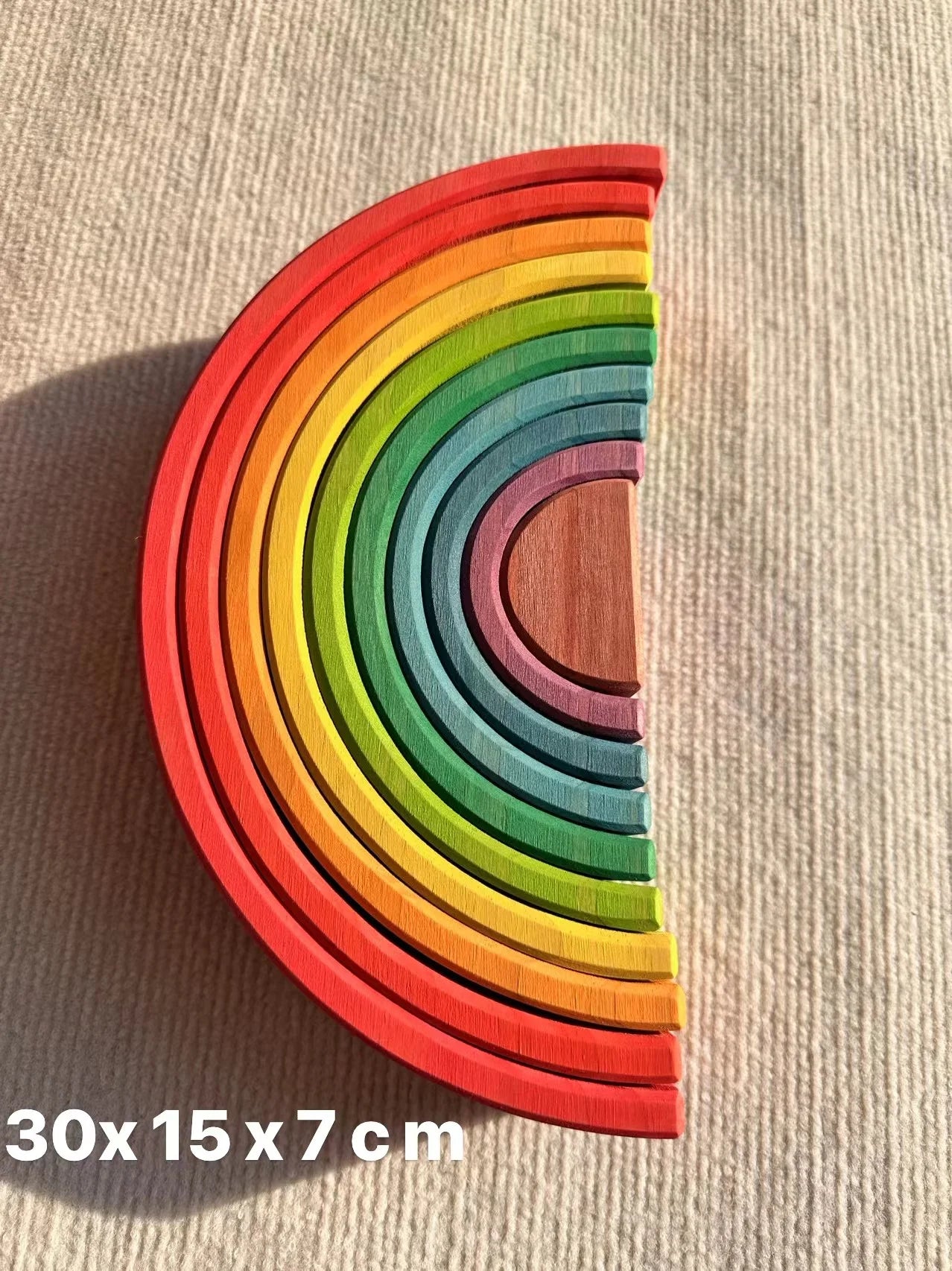 Colorful wooden rainbow toy on a beige surface with dimensions displayed.