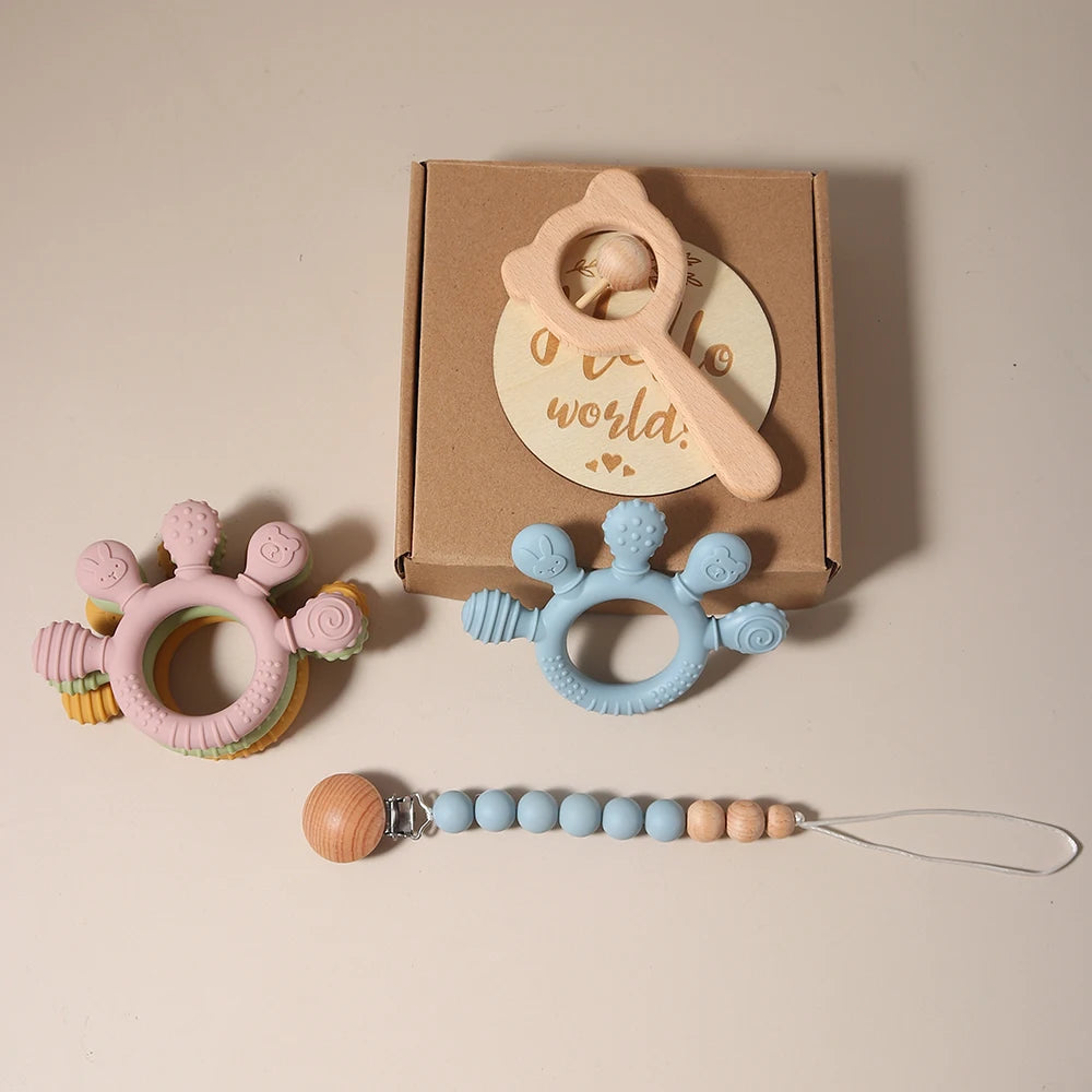 Set of baby teething toys with a pacifier clip on a beige background
