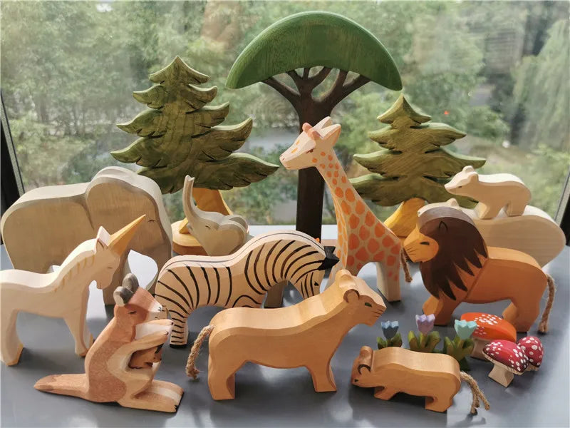 Collection of wooden animal toys with trees and plants on a reflective surface.