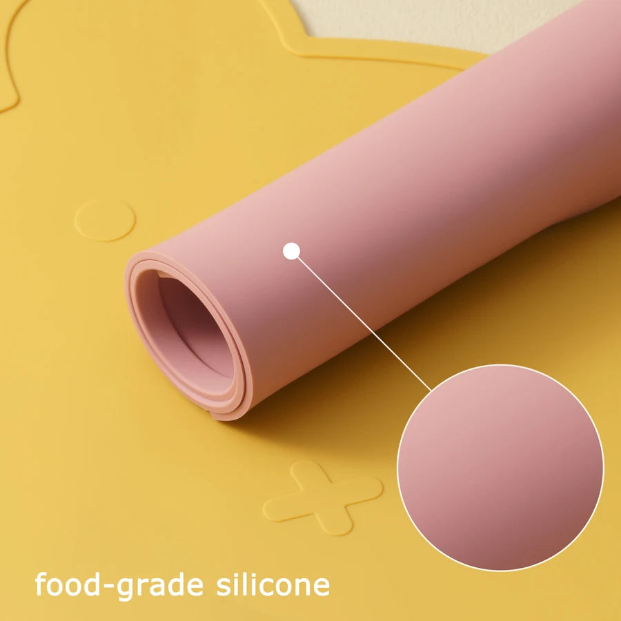 Rolled pink silicone placemat on a yellow bear placemat