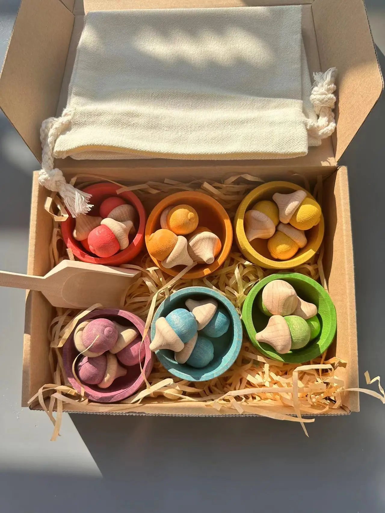 Colorful wooden toy set in a box with a white cloth on top