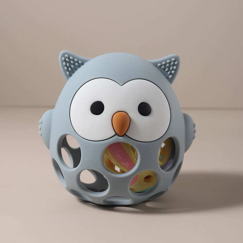 Blue owl-shaped toy with a colorful ball inside on a beige background