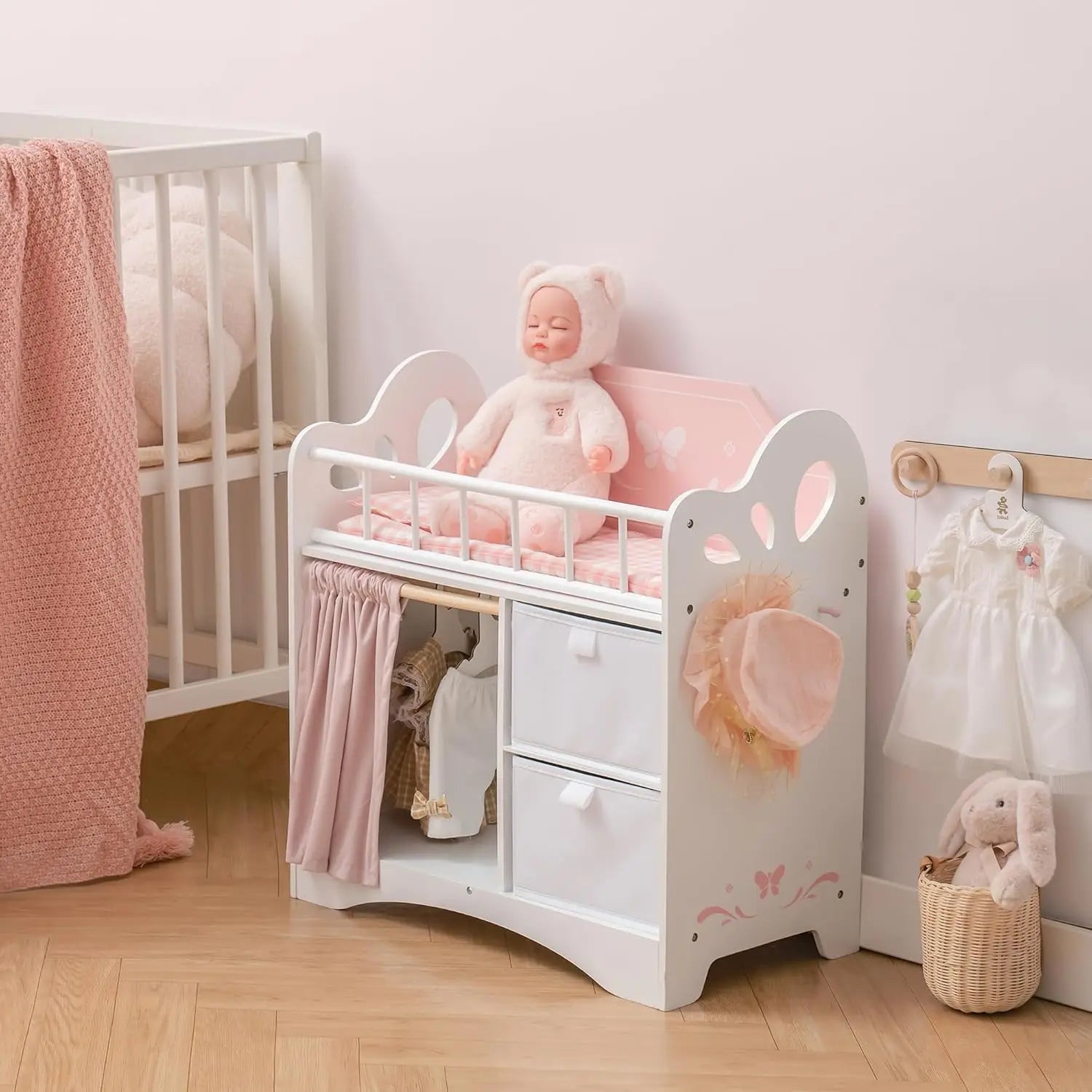 White doll bed with pink bedding and toys in a nursery setting