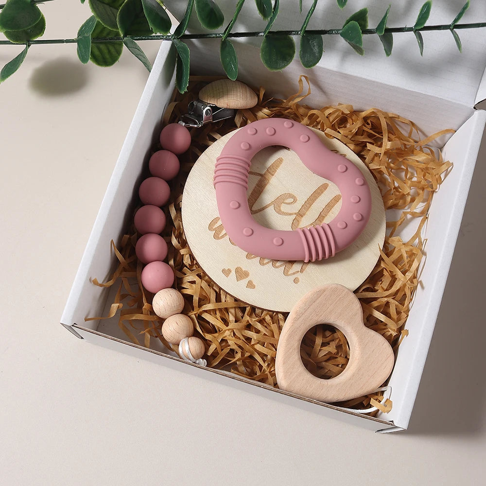 Set of baby teething toys in a gift box with a pink and wooden teether.