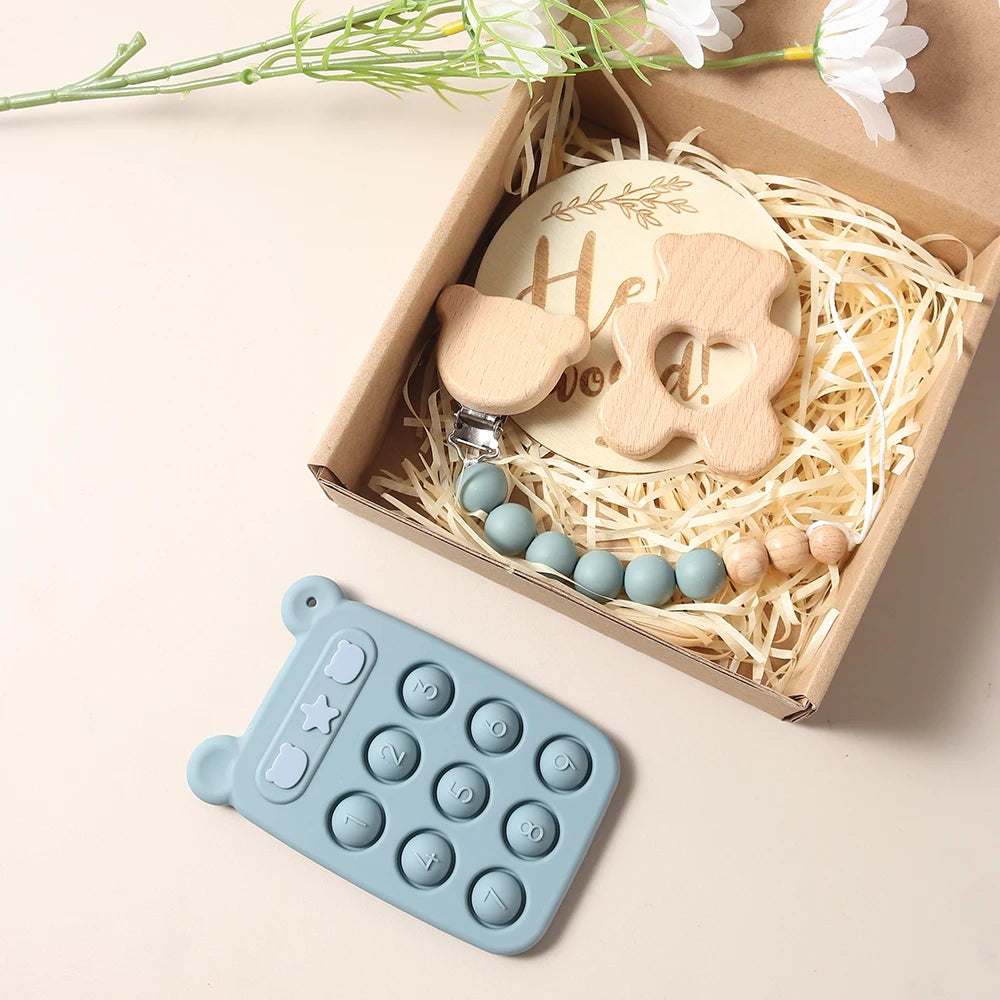Teething toy set with wooden rattle and blue silicone mold in a decorative box.