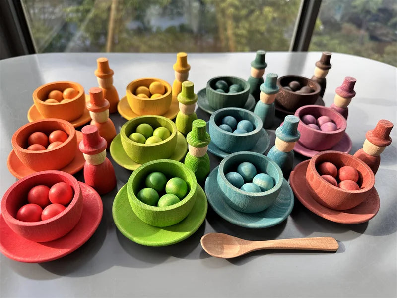 Colorful wooden toy set with bowls and a spoon on a light surface.