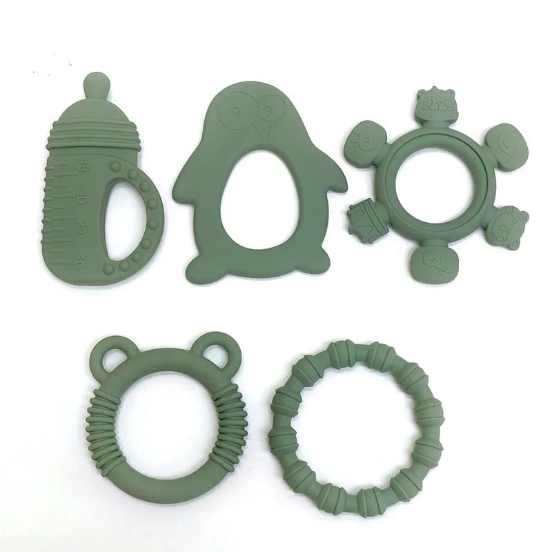 Six sage green silicone baby teething toys arranged on a plain white background, including a bottle-shaped teether, an owl teether, a rattle-shaped ring with animal faces, a bear-shaped ring, and a textured circular ring.