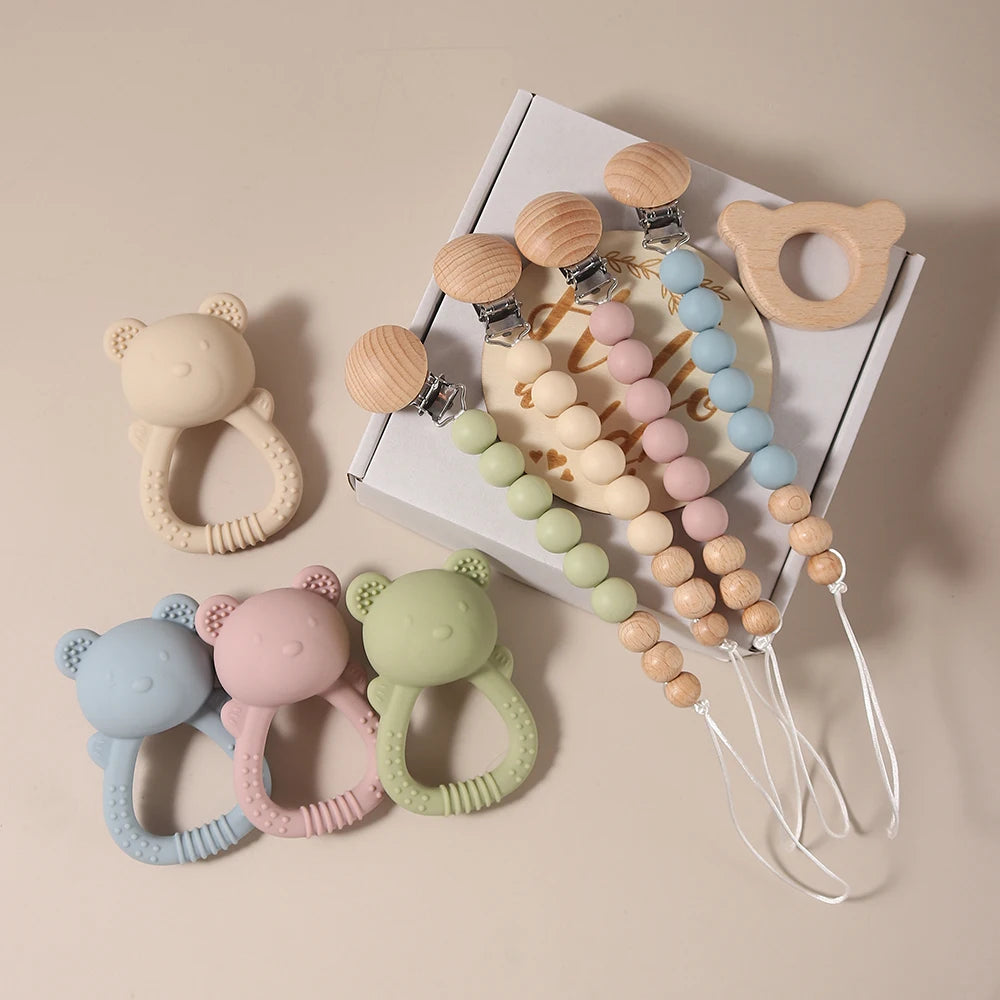 Set of colorful baby teething toys including rings and a beaded necklace on a beige background.
