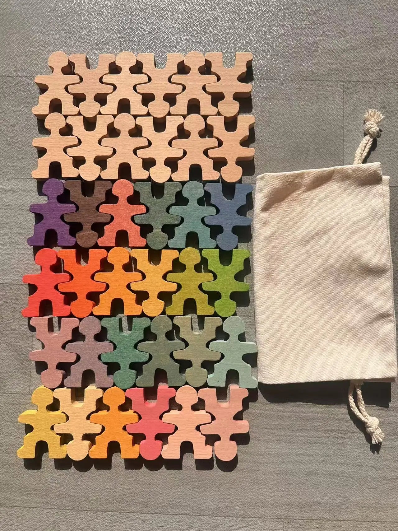 Colorful puzzle piece-shaped mats with a beige drawstring bag on a wooden surface