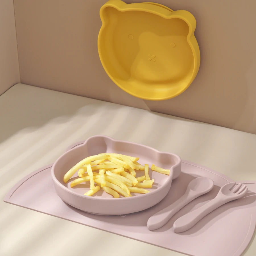 Pink bear placemat set with pasta beside a mustard plate