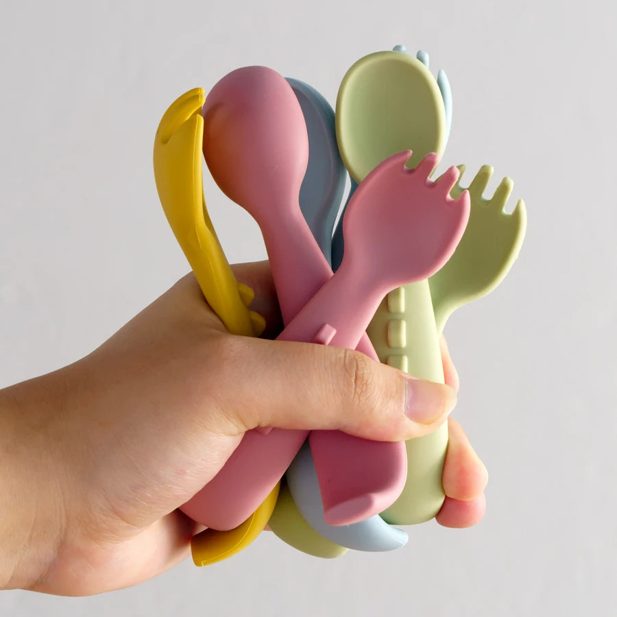 Hand holding soft silicone spoons and forks in many colors