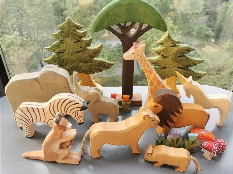 Set of wooden animal toys with trees and flowers on a reflective surface.