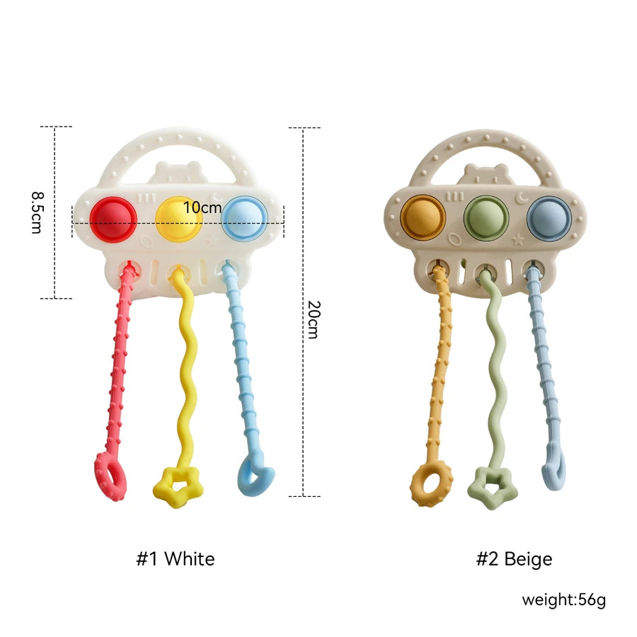 Two baby teething toys shown on a white background with measurement labels and text. The left toy is labeled #1 White and is white with red, yellow, and blue buttons plus pink, yellow, and blue dangling handles.