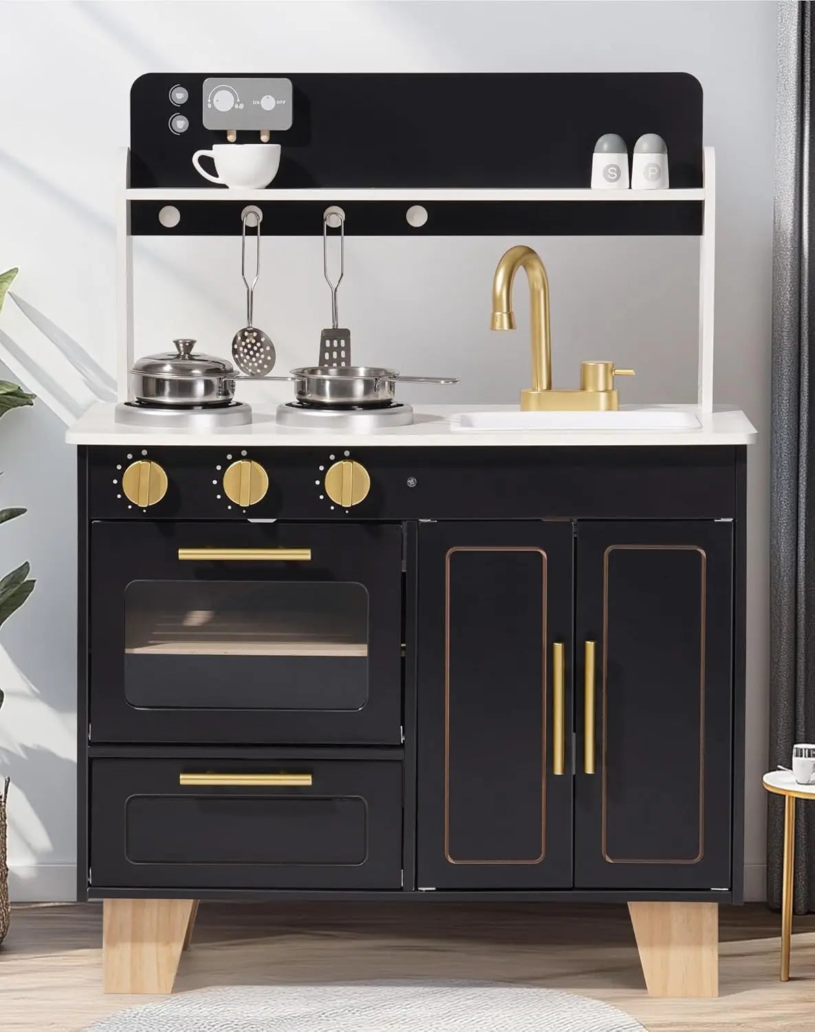 Black play kitchen set with gold accents on a light gray background