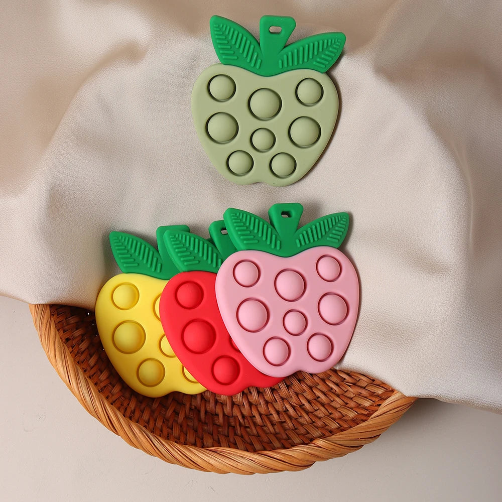 Colorful pop-it toys shaped like fruits on a woven basket with a beige cloth background