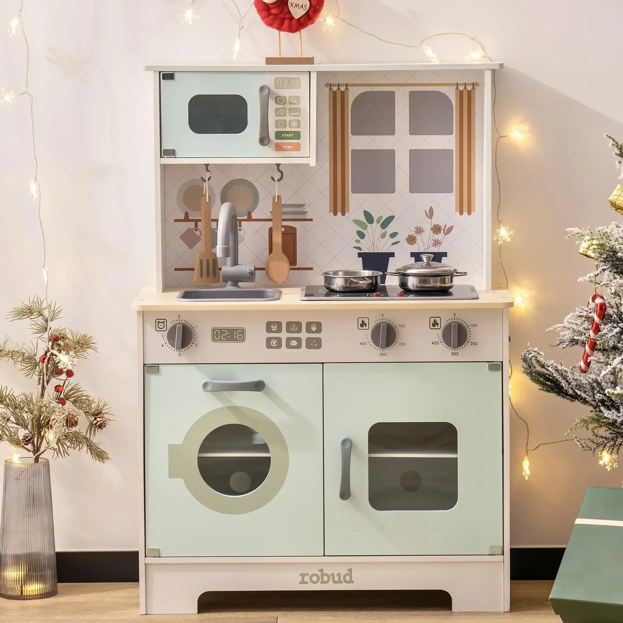 Children's play kitchen set with oven, stove, and cabinets in a festive room.