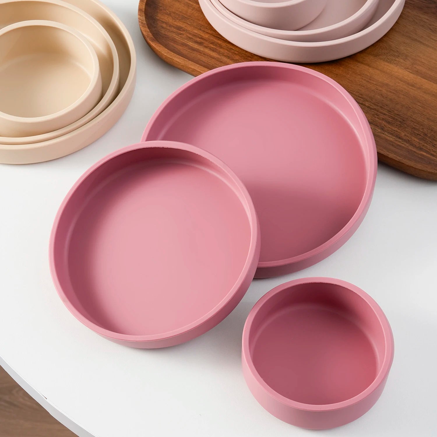 Dusty rose nesting plates beside sand colored plates