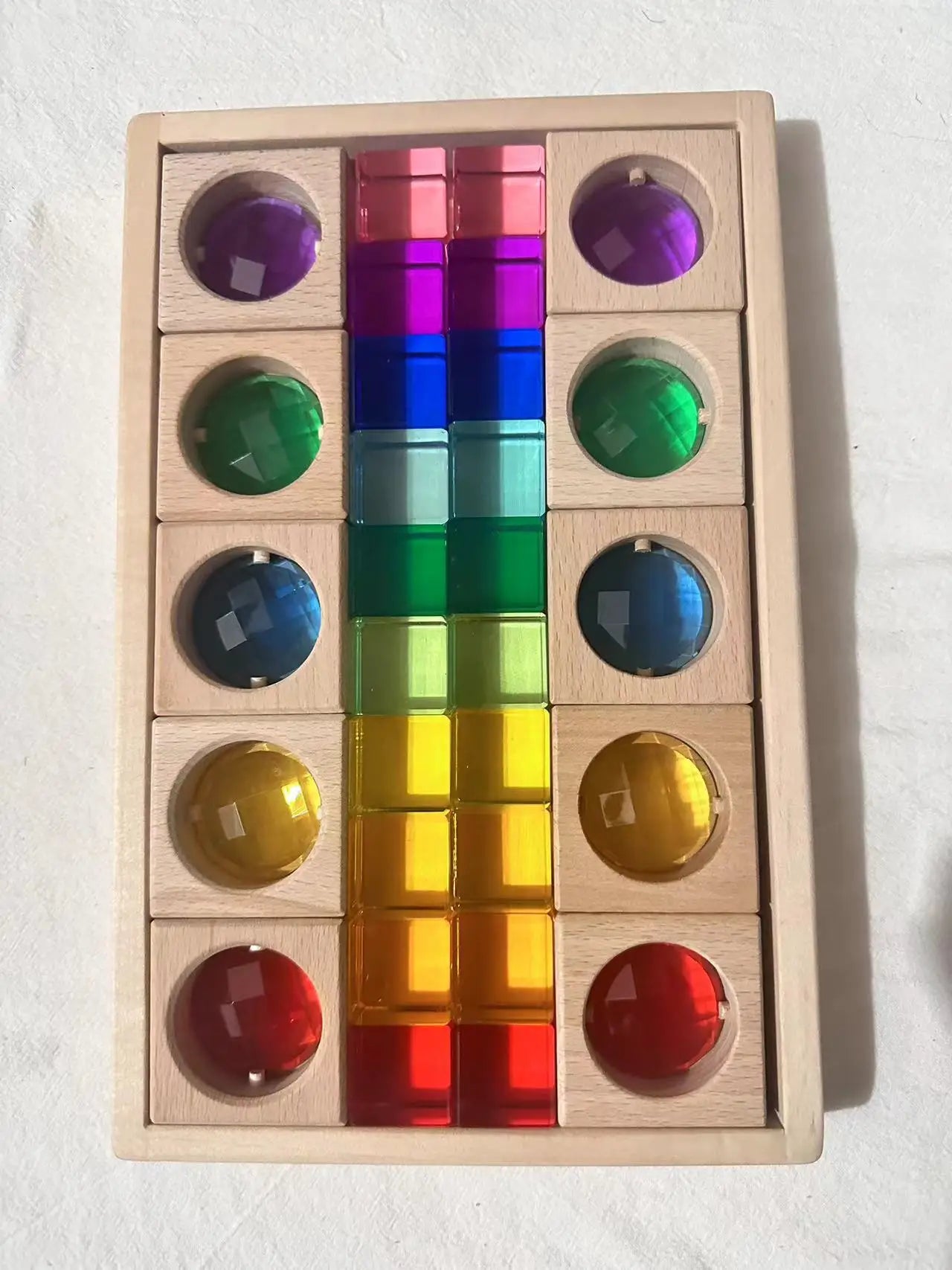 Color sorting toy with wooden frame and transparent colored blocks on a white background
